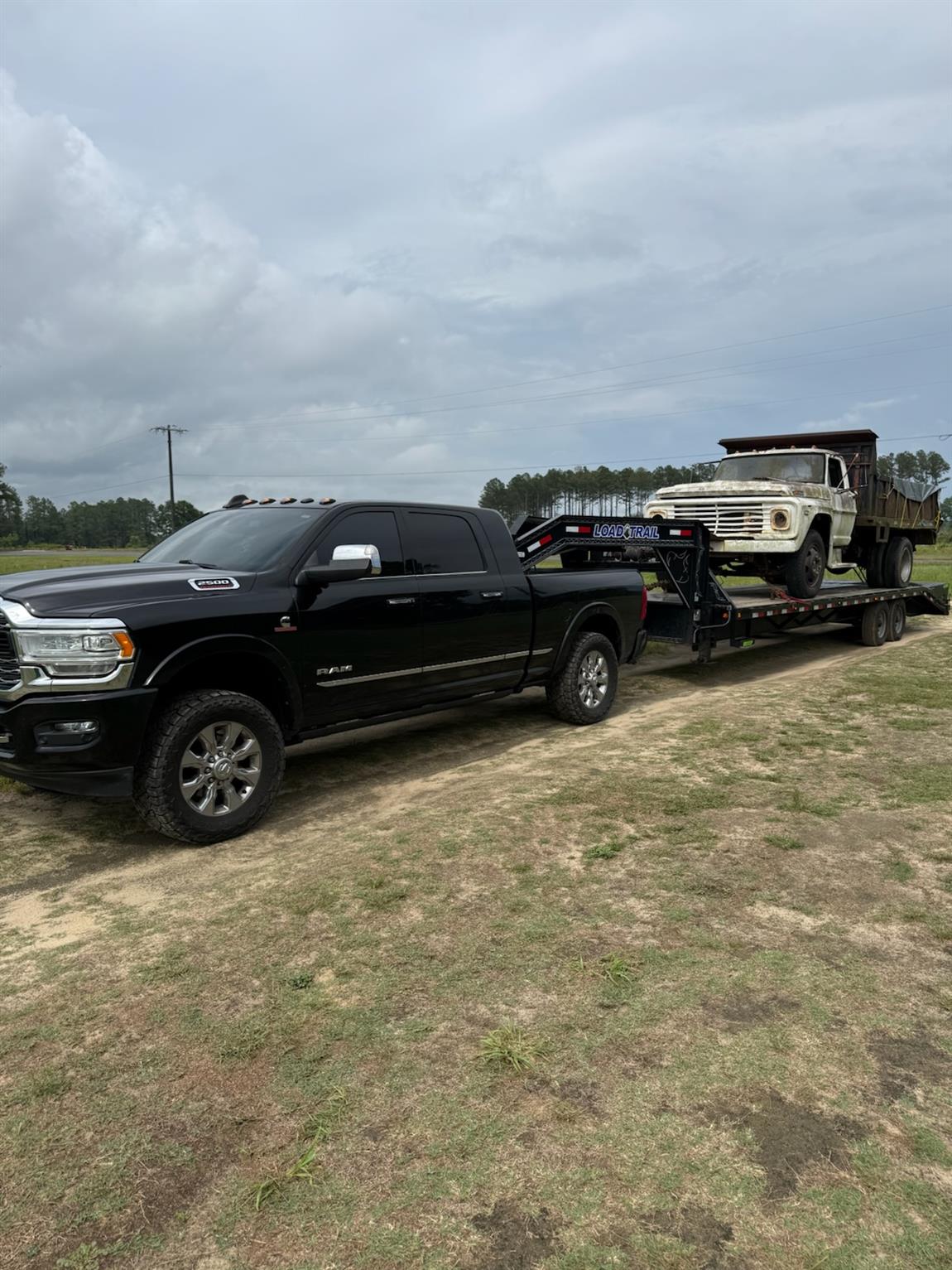 Vintage Ford dump truck loaded on the gooseneck behind a Ram 2500