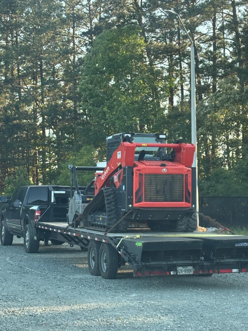 Kubota track loader chained down on a gooseneck deck behind a dually pickup