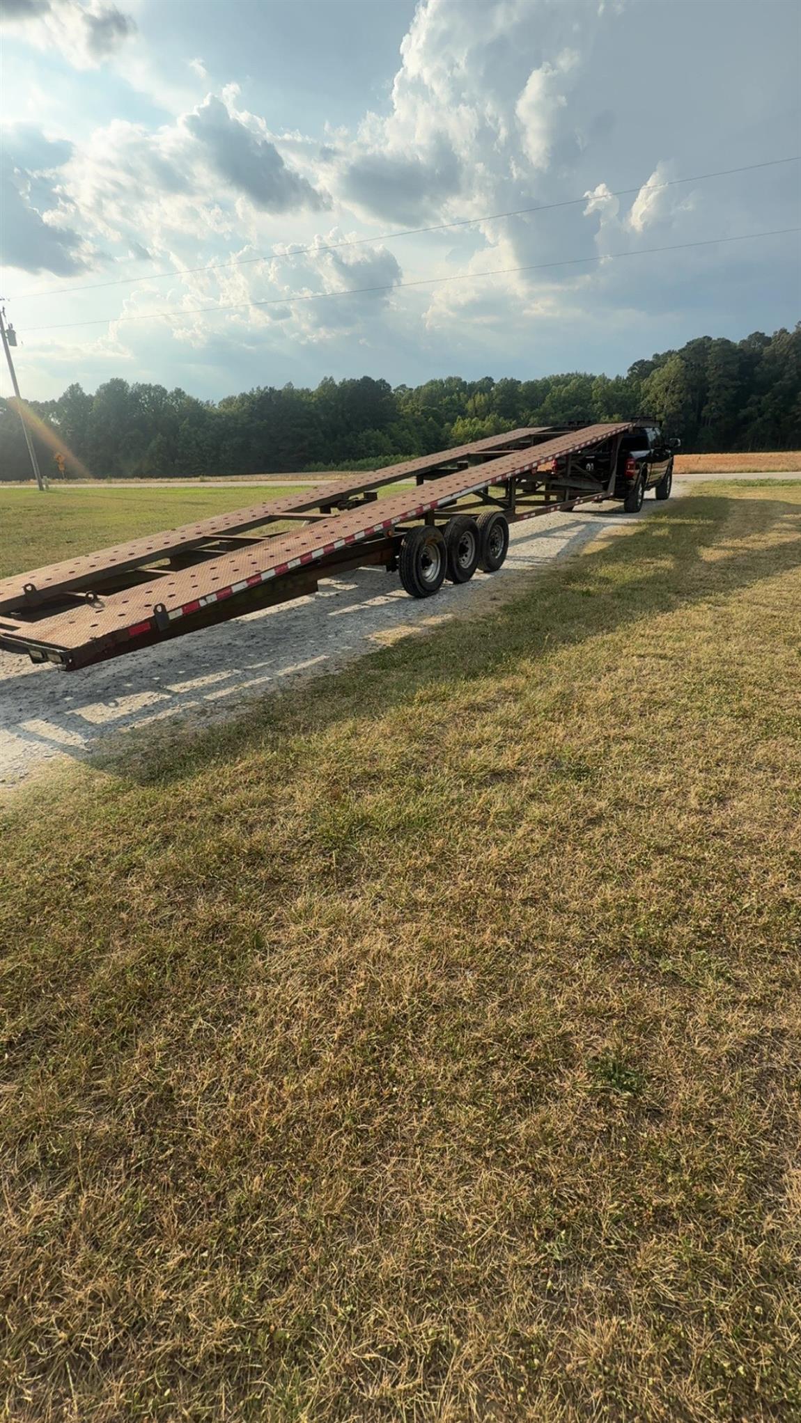 Tilt deck gooseneck trailer lowered to the ground ready to load