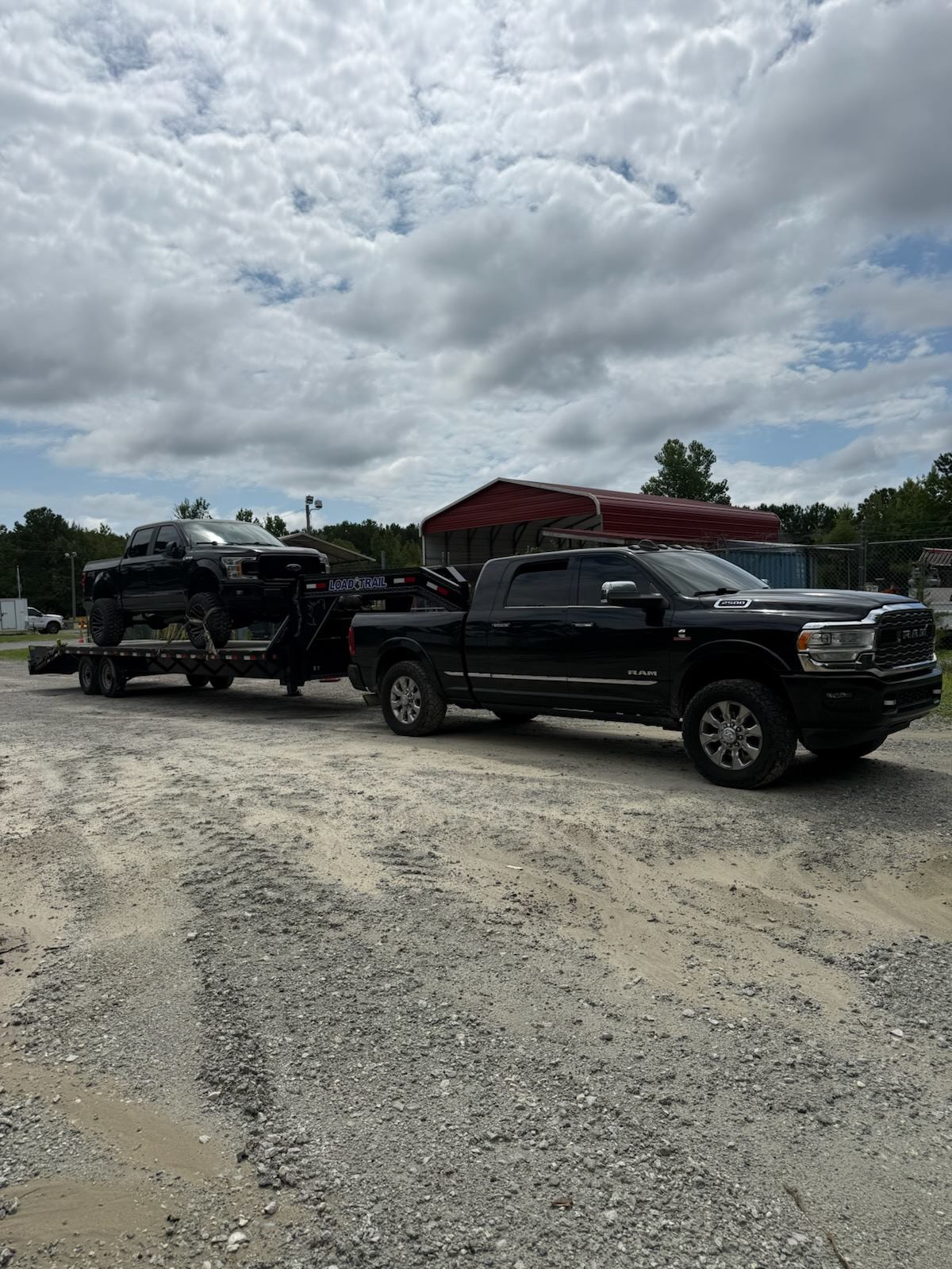 Lifted Ford F-250 chained down on a Load Trail gooseneck behind a Ram 2500